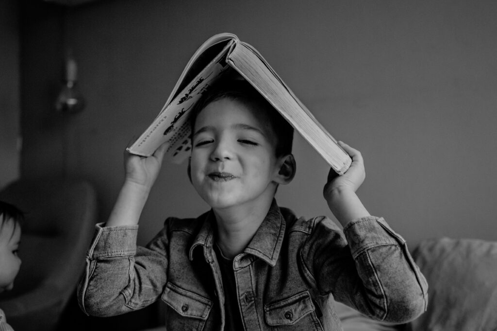 Herinneringen vastleggen. Jongen balanceert een boek op zijn hoofd en lacht speels naar de camera.