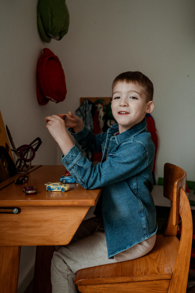 Jongen speelt met speelgoedauto’s aan zijn bureau op zijn slaapkamer.

