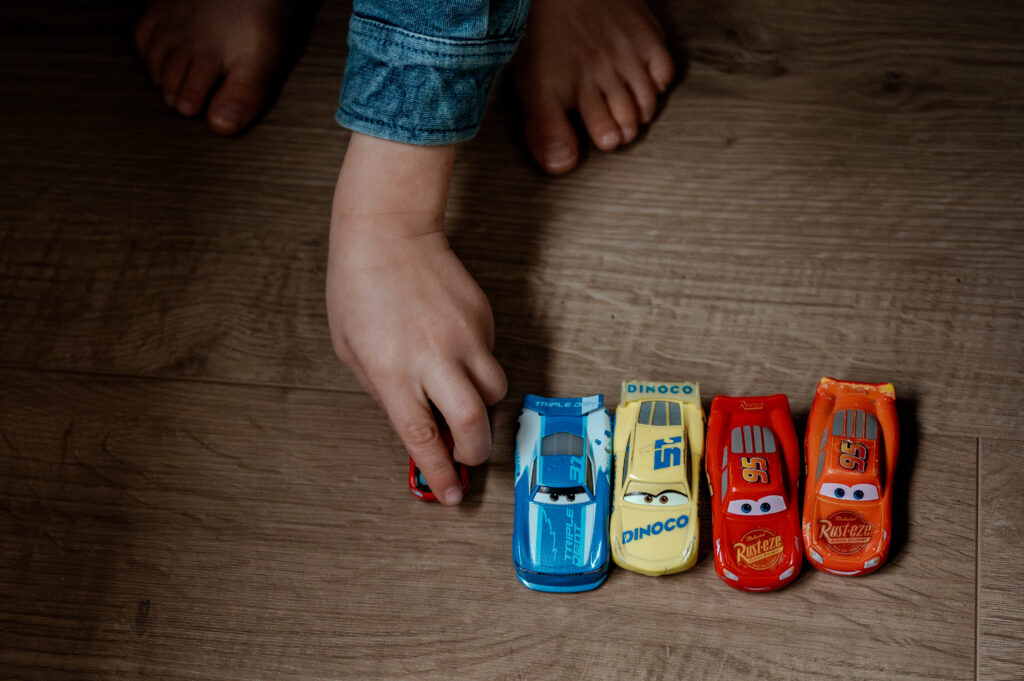 Kinderhandje schuift een speelgoedauto over de vloer.