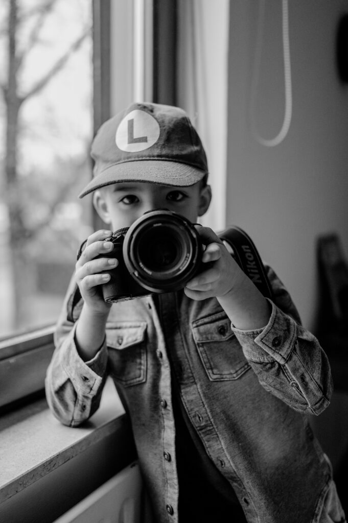 Herinneringen vastleggen. Kind speelt met een camera op zijn slaapkamer, nieuwsgierig naar fotografie.

