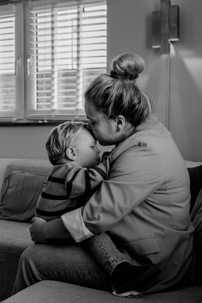 Moeder en zoon knuffelen tijdens de zwangerschapsshoot aan huis