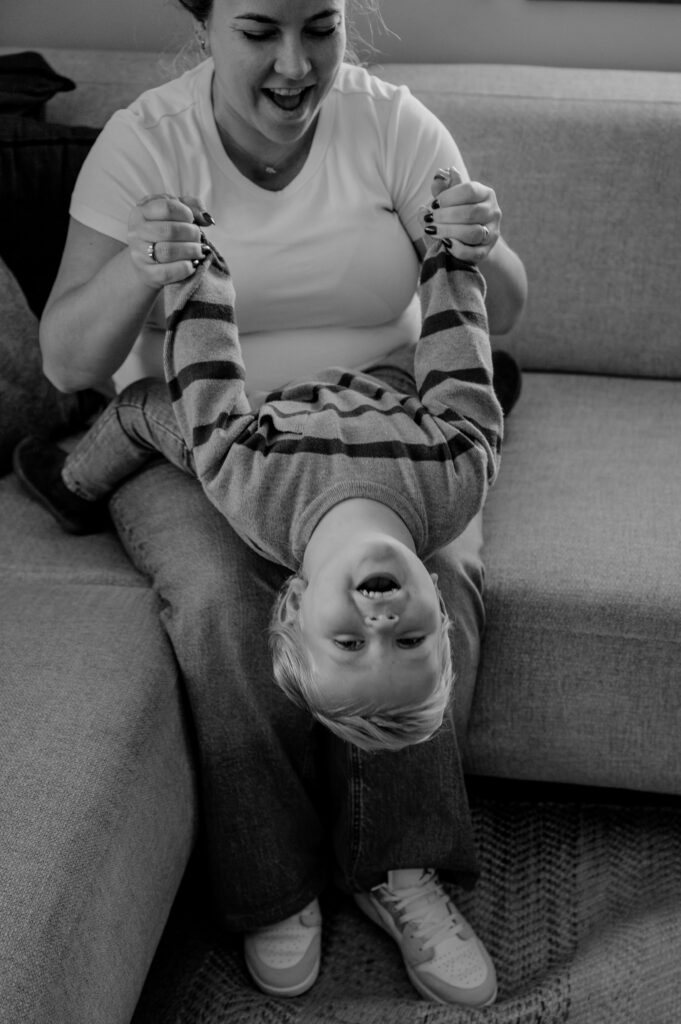 Moeder en zoon stoeien tijdens de zwangerschapsshoot