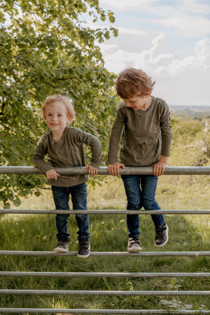 kinderen spelen op hek in het zuid-limburgse heuvelland in een shoot met Sanne Creuels Photograhy