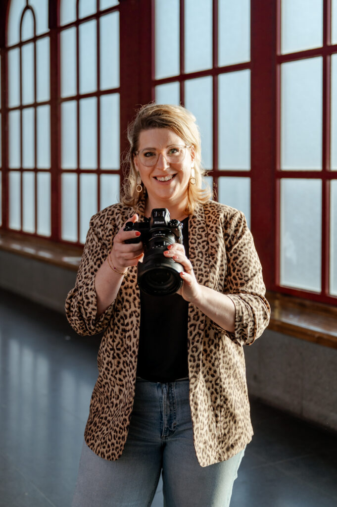 Sanne Creuels, fotograaf, poseert met haar camera. Deze foto ondersteunt de fotografiecursus.