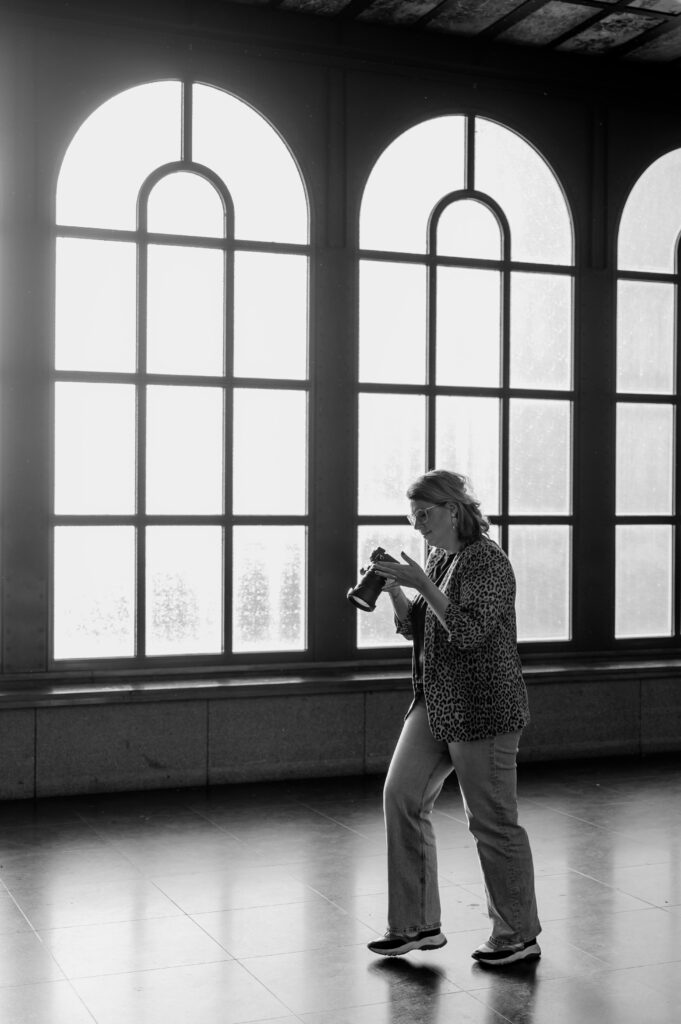 Sanne Creuels, fotograaf, maakt een foto met haar fotografiecamera. Deze foto ondersteunt de fotografiecursus.
