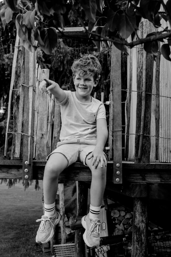Zwart wit portret van een jongen die in de boomhut zit tijdens een shoot met Sanne Creuels Photography