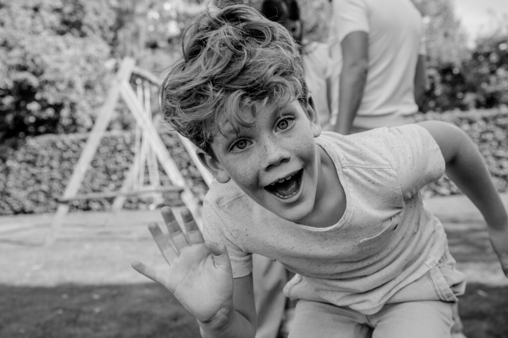 Zwart wit portret van een jongen die lekker gek doet tijdens een shoot met Sanne Creuels Photography