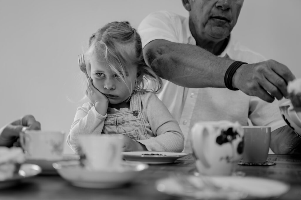 Sanne Creuëls Photography - zwart wit foto van een teleurgesteld kind dat in de keuken moet wachten op vlaai tijdens hun familieshoot in Zuid-Limburg