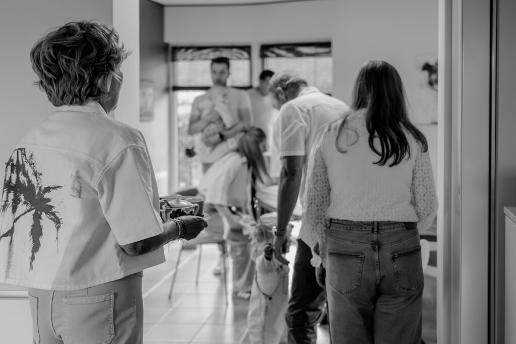 Sanne Creuëls Photography - zwart wit foto van een familie die zich verzamelt in de keuken van hun ouderlijk huis tijdens hun familieshoot in Zuid-Limburg